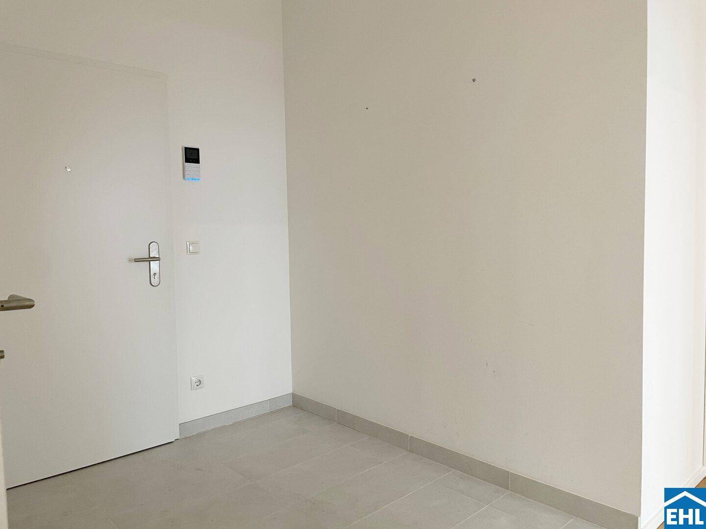 Leerer Eingangsbereich mit heller Fliese und weißer Tür, bereit zur Einrichtung.