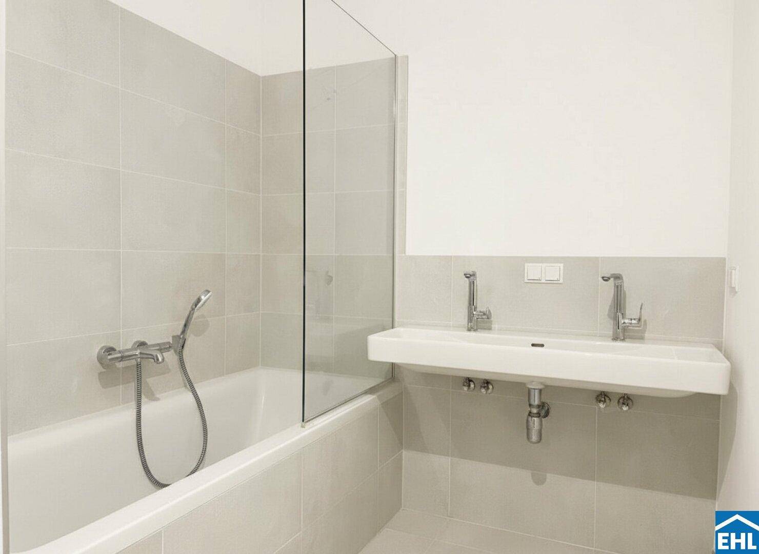 Helles Badezimmer mit Badewanne, Glasabtrennung und Doppelwaschbecken, unmöbliert.