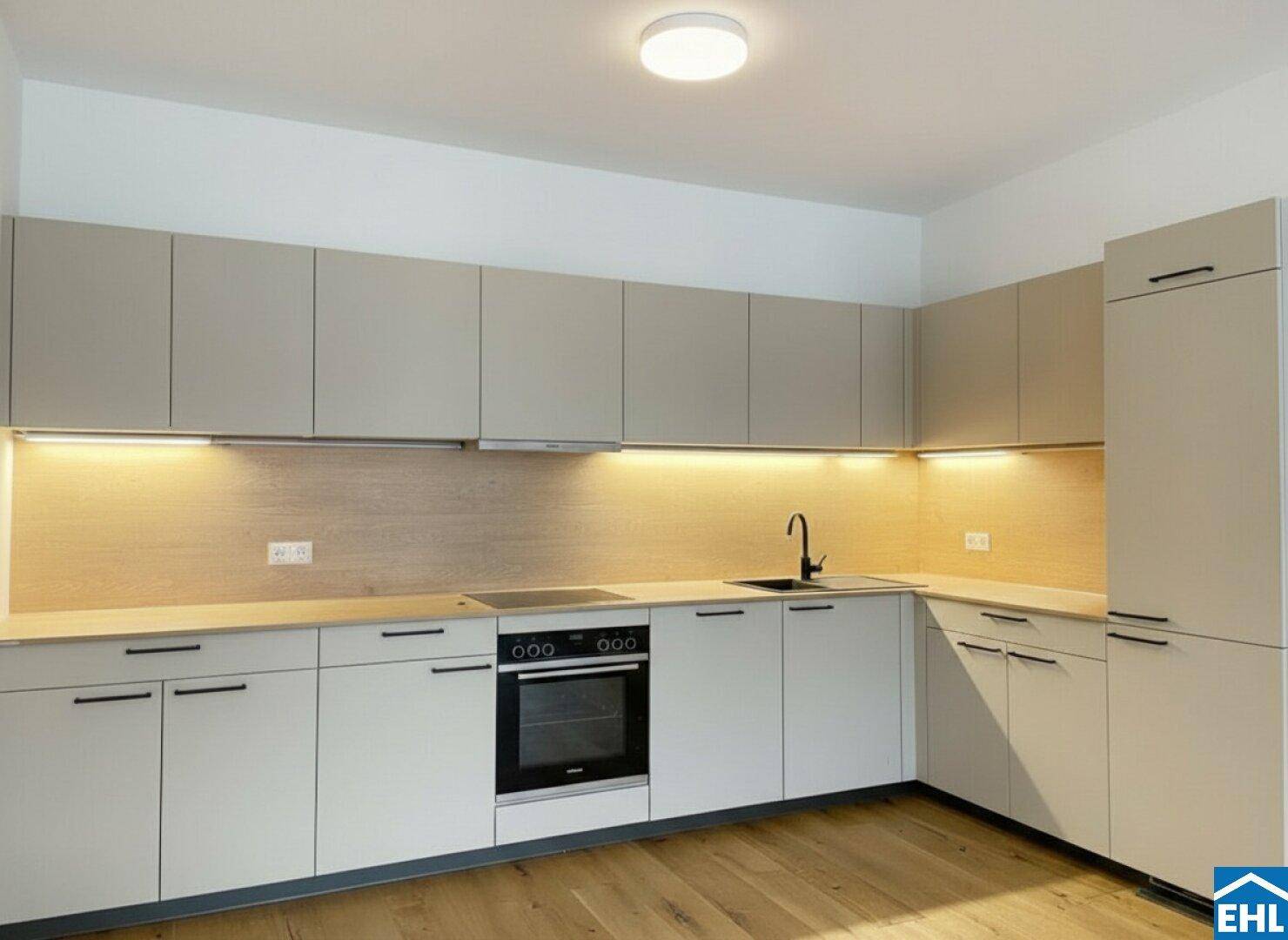 Moderne Einbauküche mit hellen Schränken, integriertem Backofen und Holzrückwand.