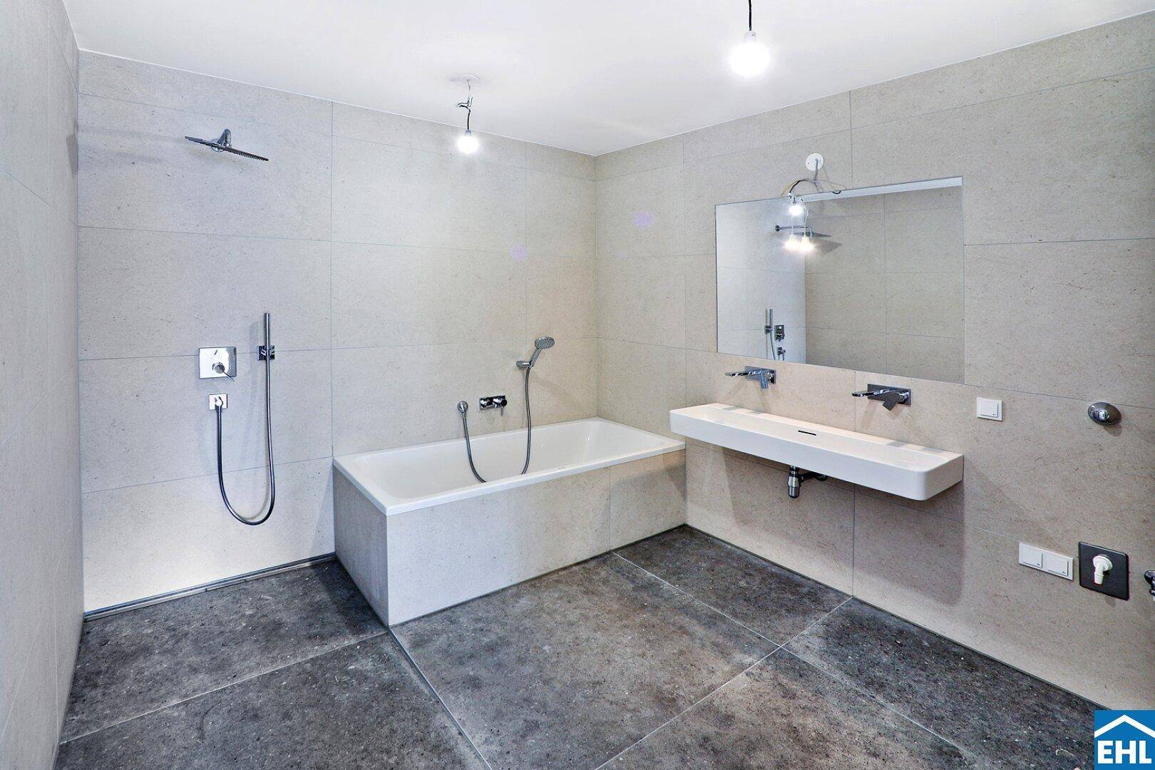 Modernes Badezimmer mit Badewanne, Dusche und großformatigen Fliesen.