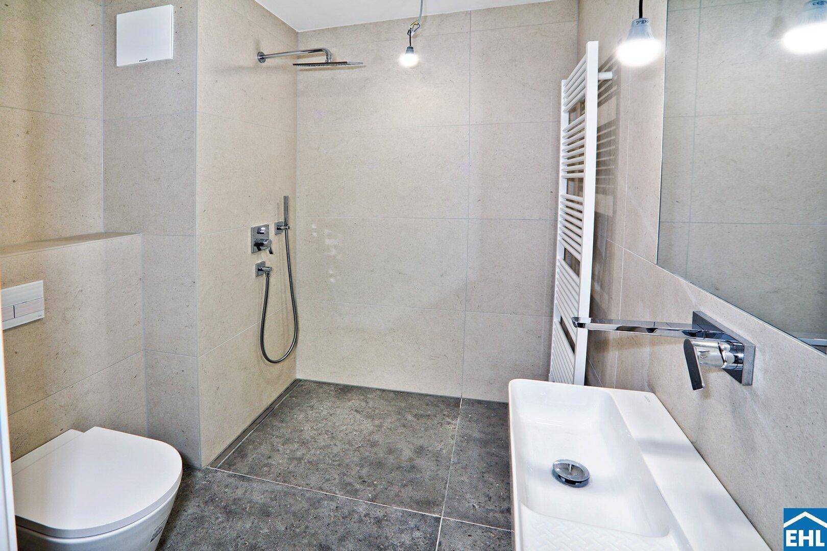 Zeitgemäßes Badezimmer mit ebenerdiger Dusche, WC und beheiztem Handtuchhalter.