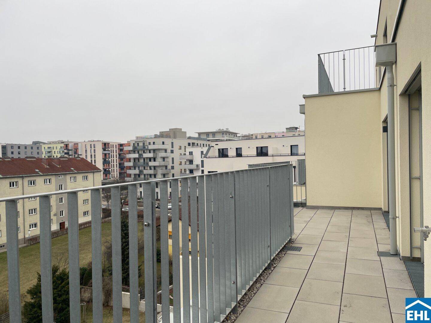 Geräumige Dachterrasse mit Metallgeländer und Blick auf die umliegenden Gebäude der Stadt.