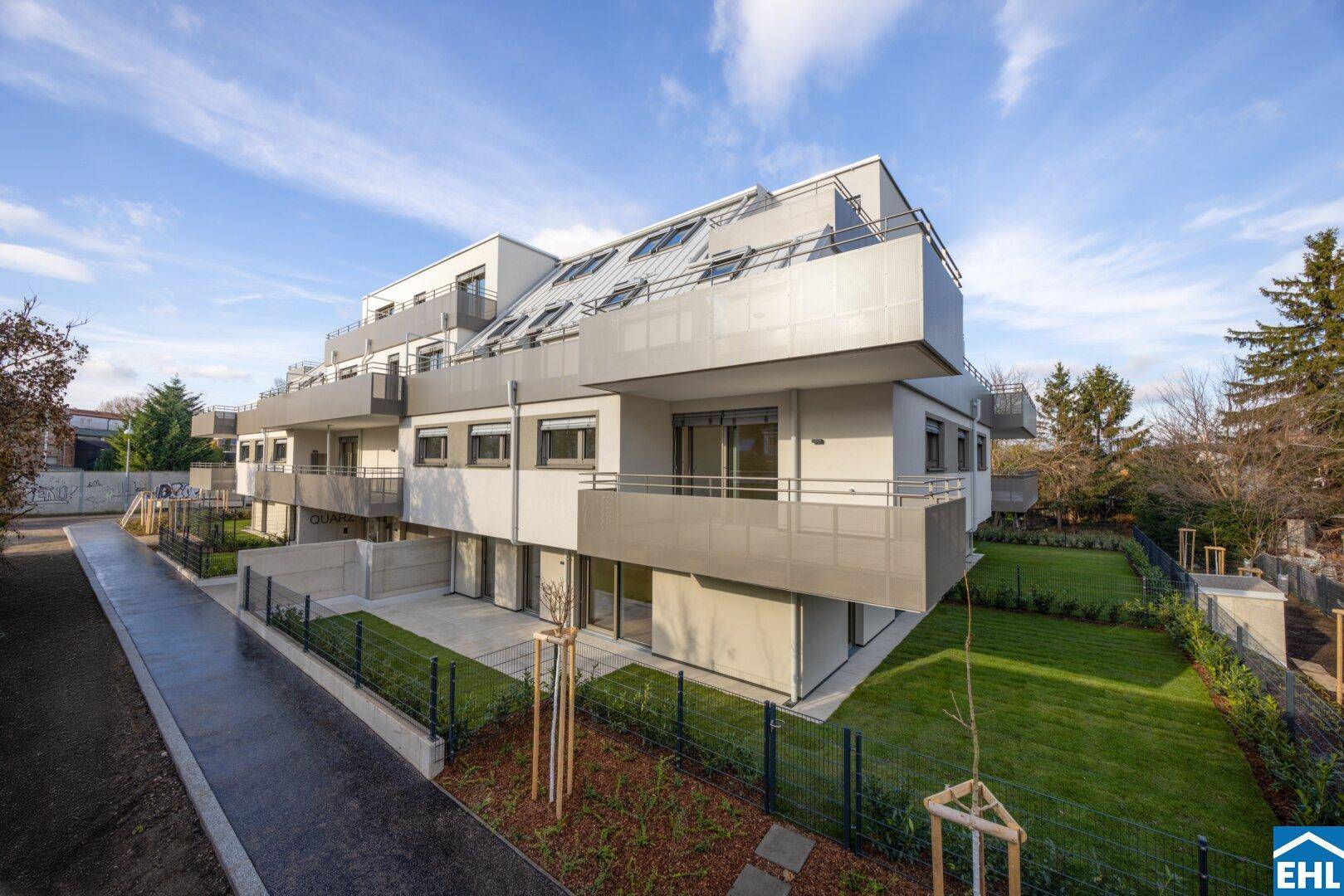 Modernes Mehrfamilienhaus mit mehreren Balkonen und Gärten in einer ruhigen Wohngegend.