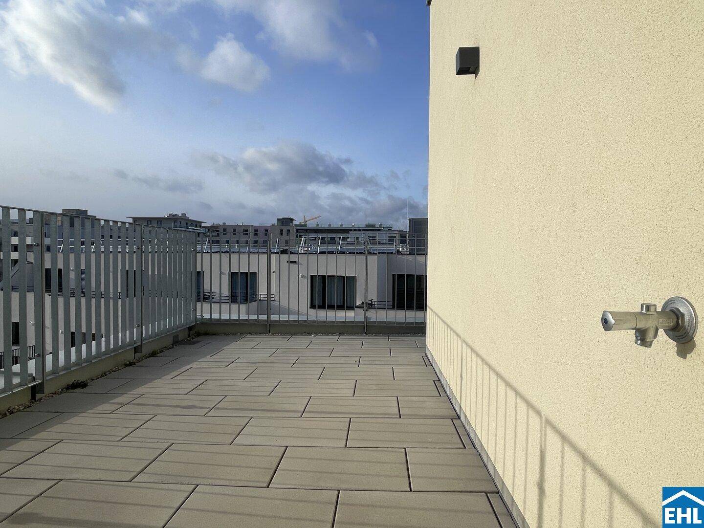 Geräumige Dachterrasse mit Fliesenboden und Blick auf die umliegenden Gebäude.