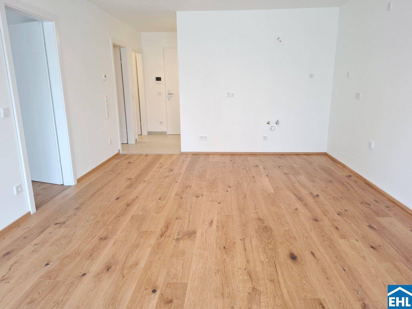 Heller, leerer Raum mit hochwertigem Holzparkett und weißen Wänden.