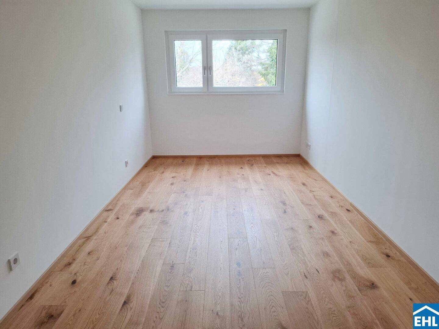 Heller Raum mit Parkettboden und Fenster, geeignet als Schlaf- oder Arbeitszimmer.
