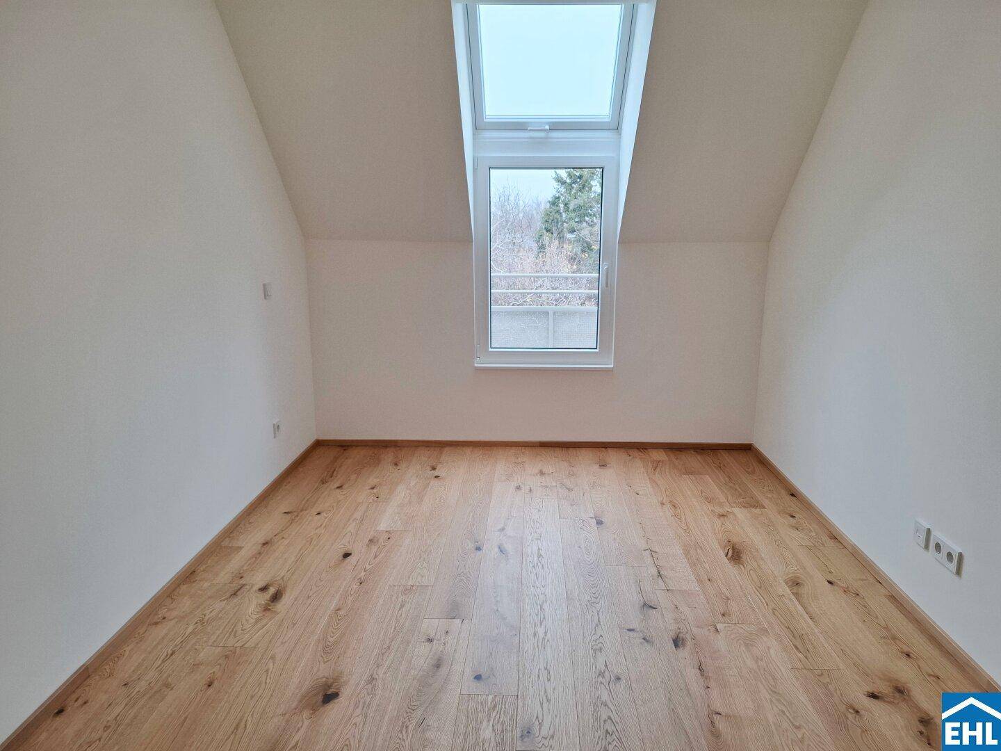Helles Schlafzimmer im Dachgeschoss mit schrägem Dach und großem Dachfenster für viel Tageslicht.