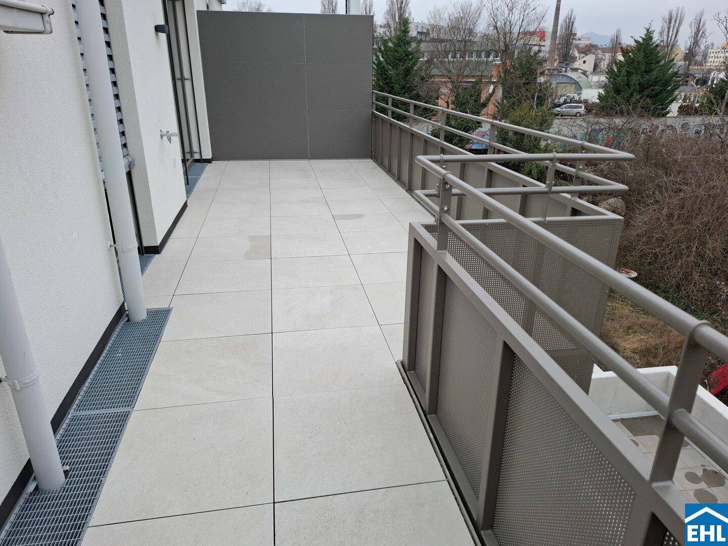 Geräumiger Balkon mit Fliesenboden und Metallgeländer, bietet Platz für Outdoor-Möbel.