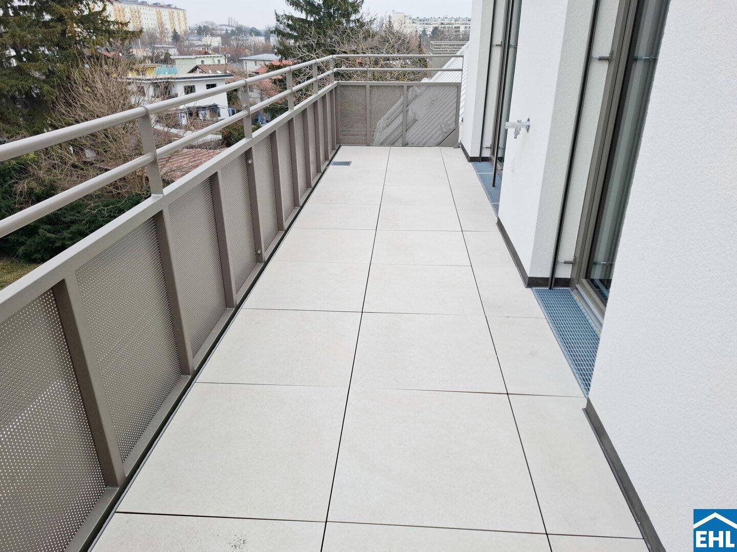 Langer, gefliester Balkon mit Metallgeländer und Blick auf die umliegende Wohngegend.