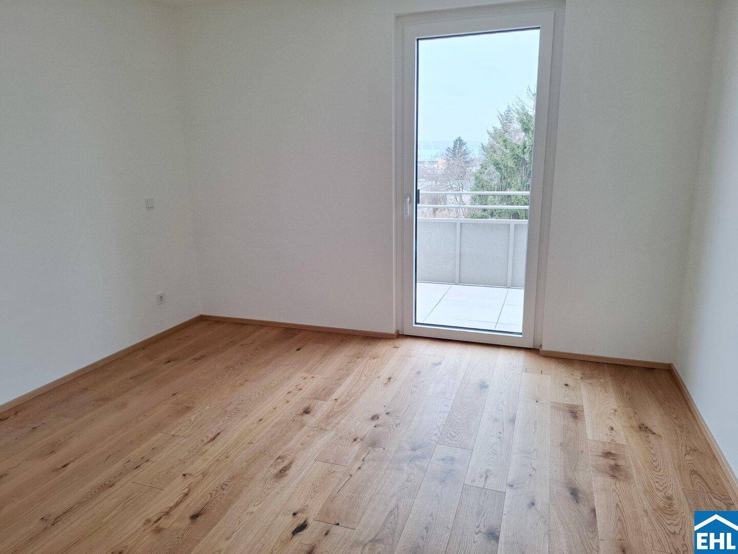 Helles Zimmer mit Holzboden und direktem Zugang zu einem privaten Balkon.