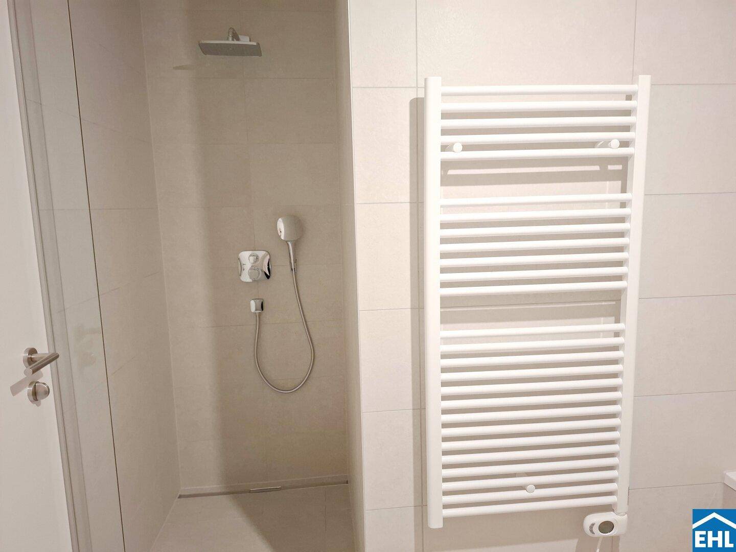 Modernes Badezimmer mit großer Duschkabine, Regenbrause und beheiztem Handtuchhalter.