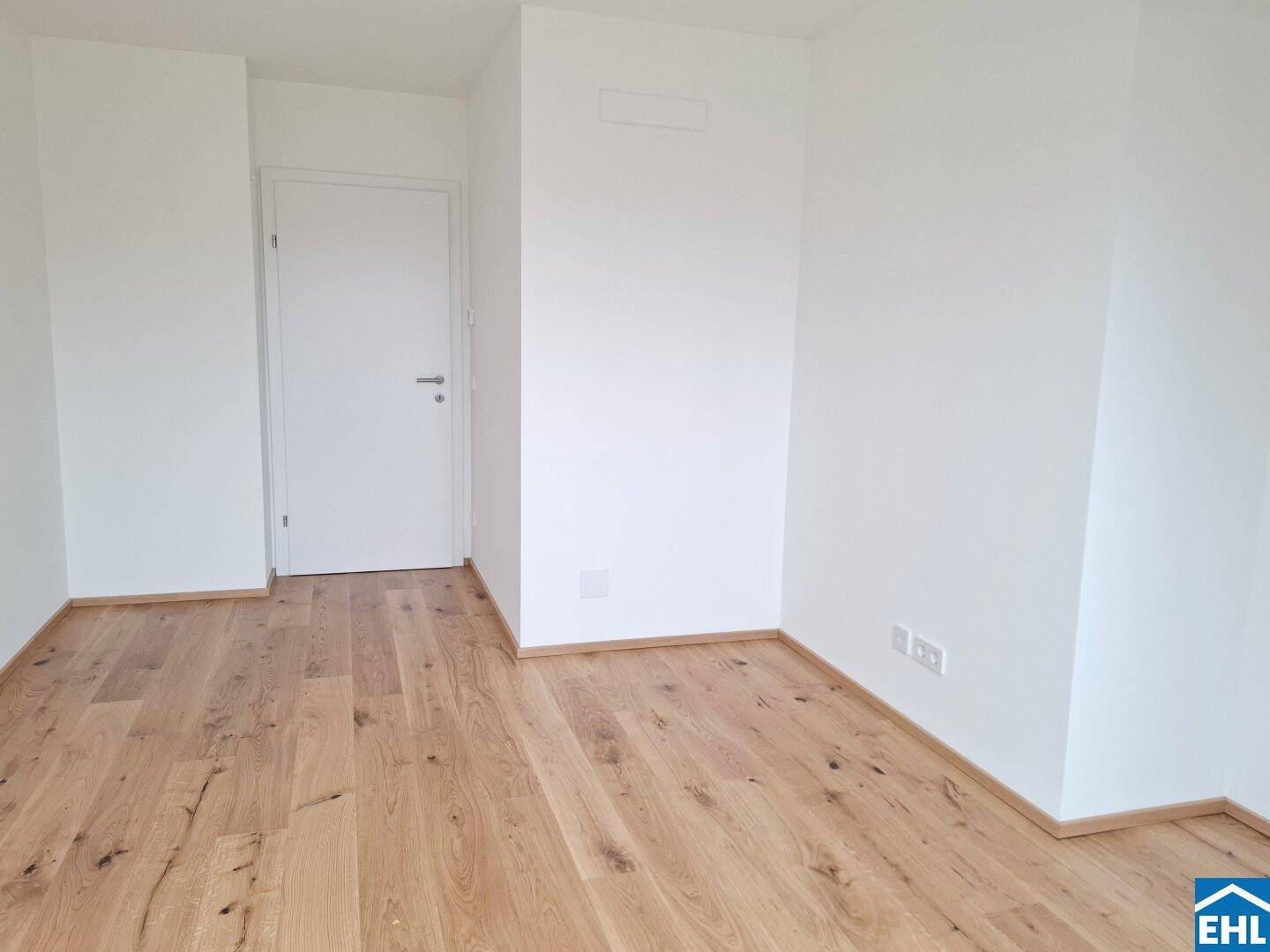 Leeres Zimmer mit hellem Parkettboden und weiß gestrichenen Wänden, ideal als Schlaf- oder Arbeitszimmer.