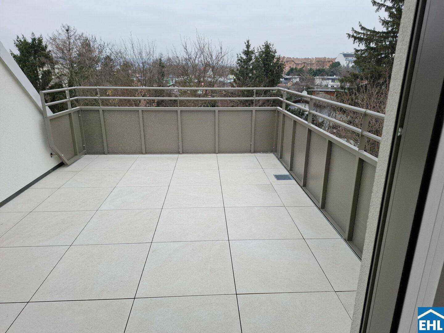 Geräumiger Balkon mit Fliesenboden und Metallgeländer, bietet einen weiten Blick über die Umgebung.