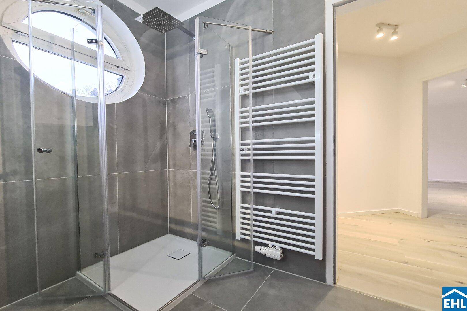Modernes Badezimmer mit großer Glasdusche, Regenbrause und beheiztem Handtuchhalter.