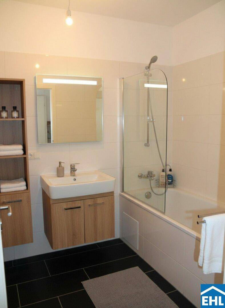 Modernes Badezimmer mit Badewanne, Duschabtrennung und dunklen Bodenfliesen.