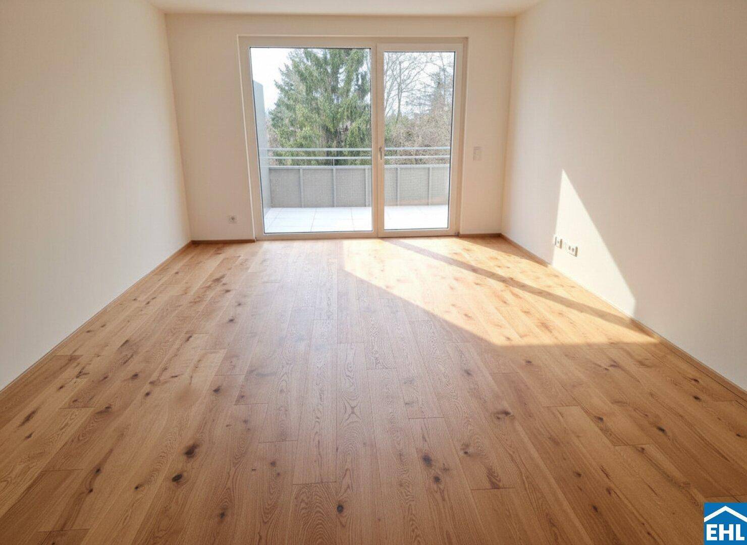 Lichtdurchfluteter Raum mit Holzboden und großem Fenster mit Balkonzugang.