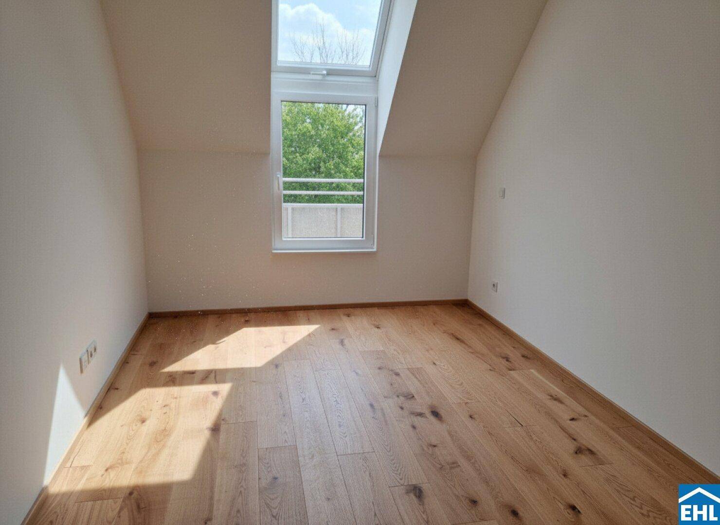 Heller Dachraum mit Holzboden, Dachschräge und Oberlichtfenster mit französischem Balkon.