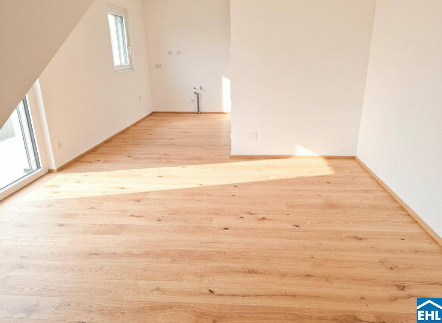 Heller, leerer Raum mit Holzboden und Zugang zu einem Balkon oder einer Terrasse.