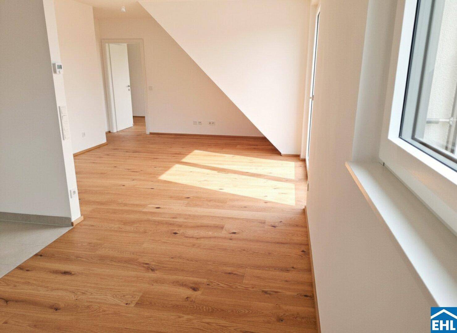 Heller Flur mit Holzboden und viel Tageslicht, der zu weiteren Räumen führt.