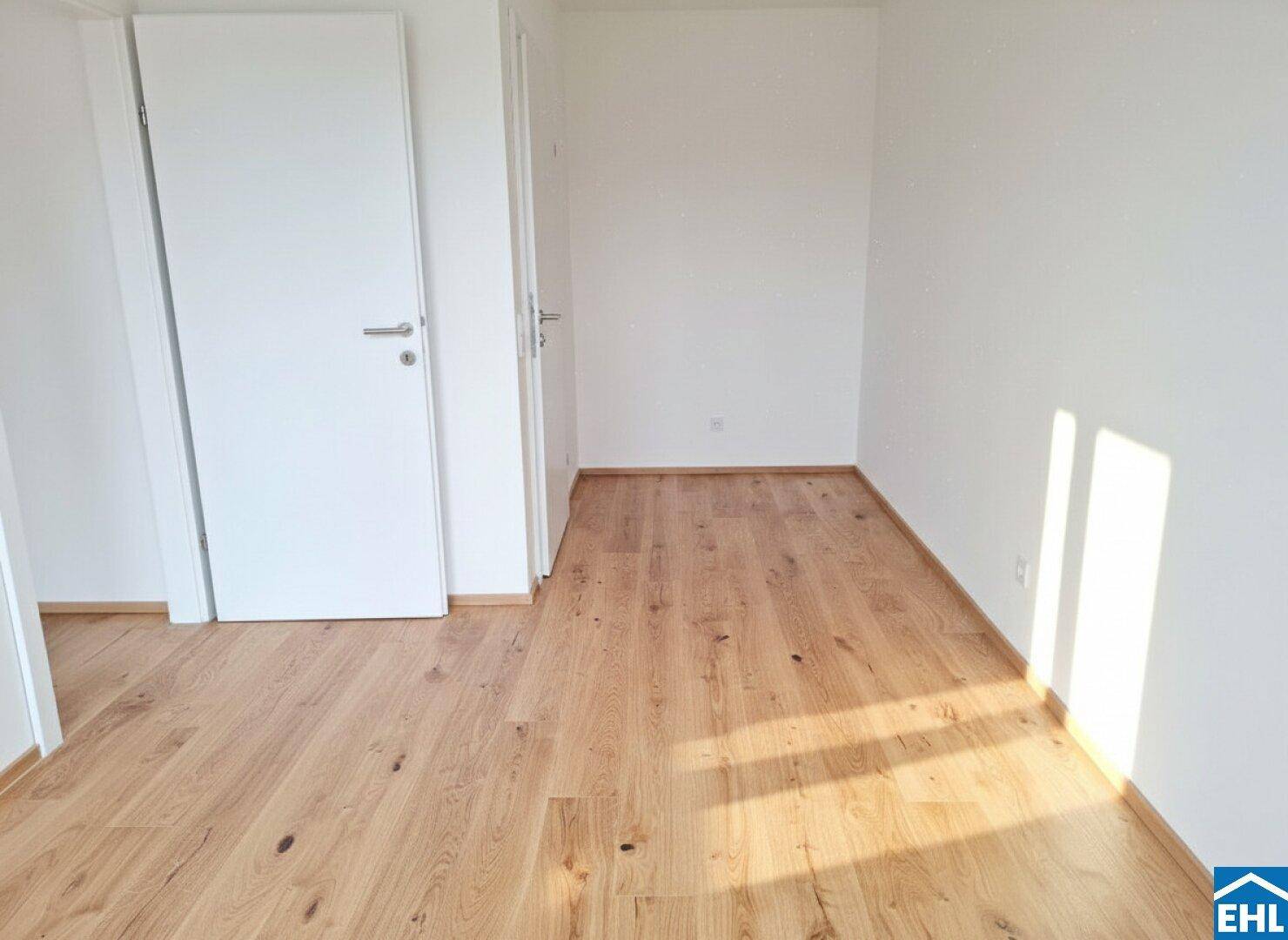 Leeres Zimmer mit Holzboden und weißen Wänden, bereit zur individuellen Gestaltung.