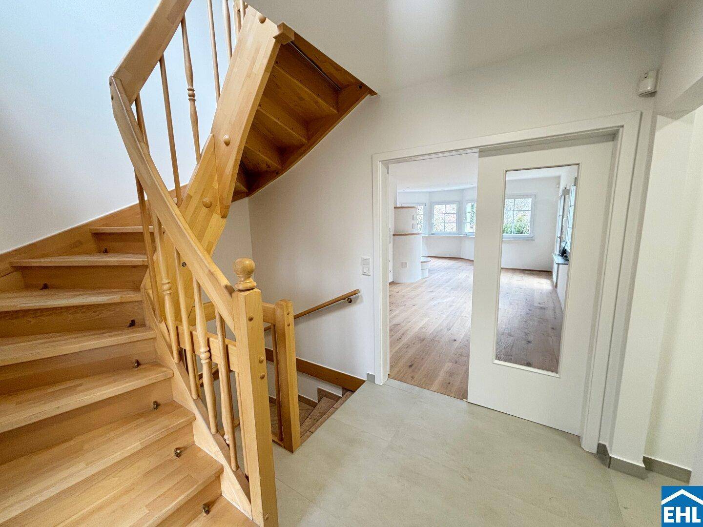 Heller Flur mit Holztreppe und Schiebetür, die zum Wohnbereich führt.