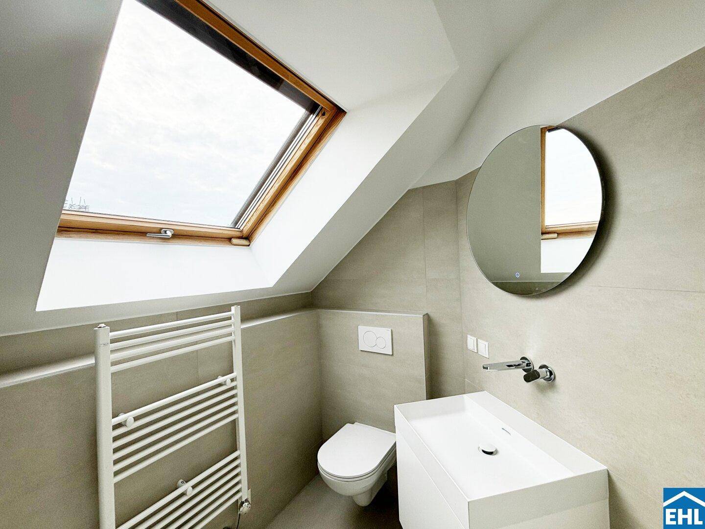 Modernes Badezimmer im Dachgeschoss mit Dachfenster, wandhängendem WC und Einzelwaschbecken.