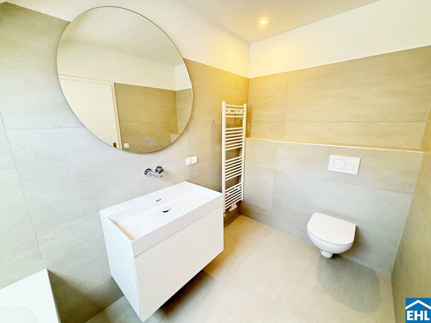 Modernes Badezimmer mit wandhängendem WC, Einzelwaschbecken und beheiztem Handtuchhalter.