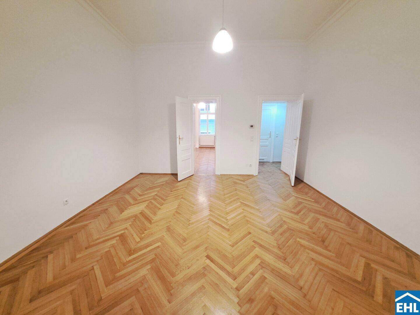 Geräumiger Raum mit Fischgrätparkett und hohen Decken, ideal für Wohn- oder Schlafzimmer.