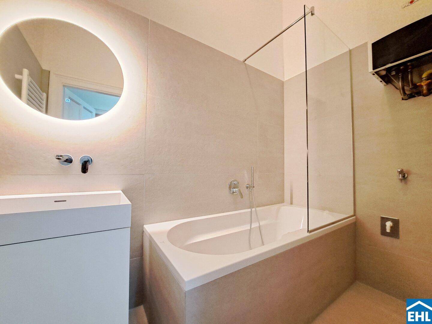 Elegantes Badezimmer mit Badewanne, Glasabtrennung und modernen Armaturen.