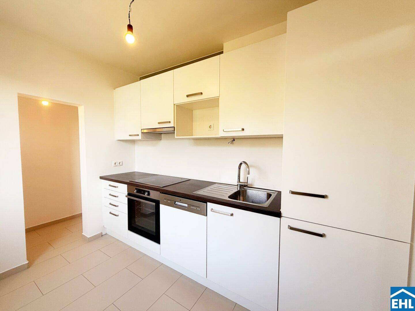 Moderne Einbauküche mit weißen Hochglanzfronten, dunkler Arbeitsplatte und integrierten Geräten.