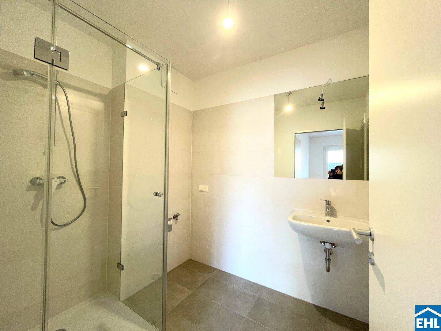 Modernes Badezimmer mit Duschkabine, Waschbecken und großem Spiegel.