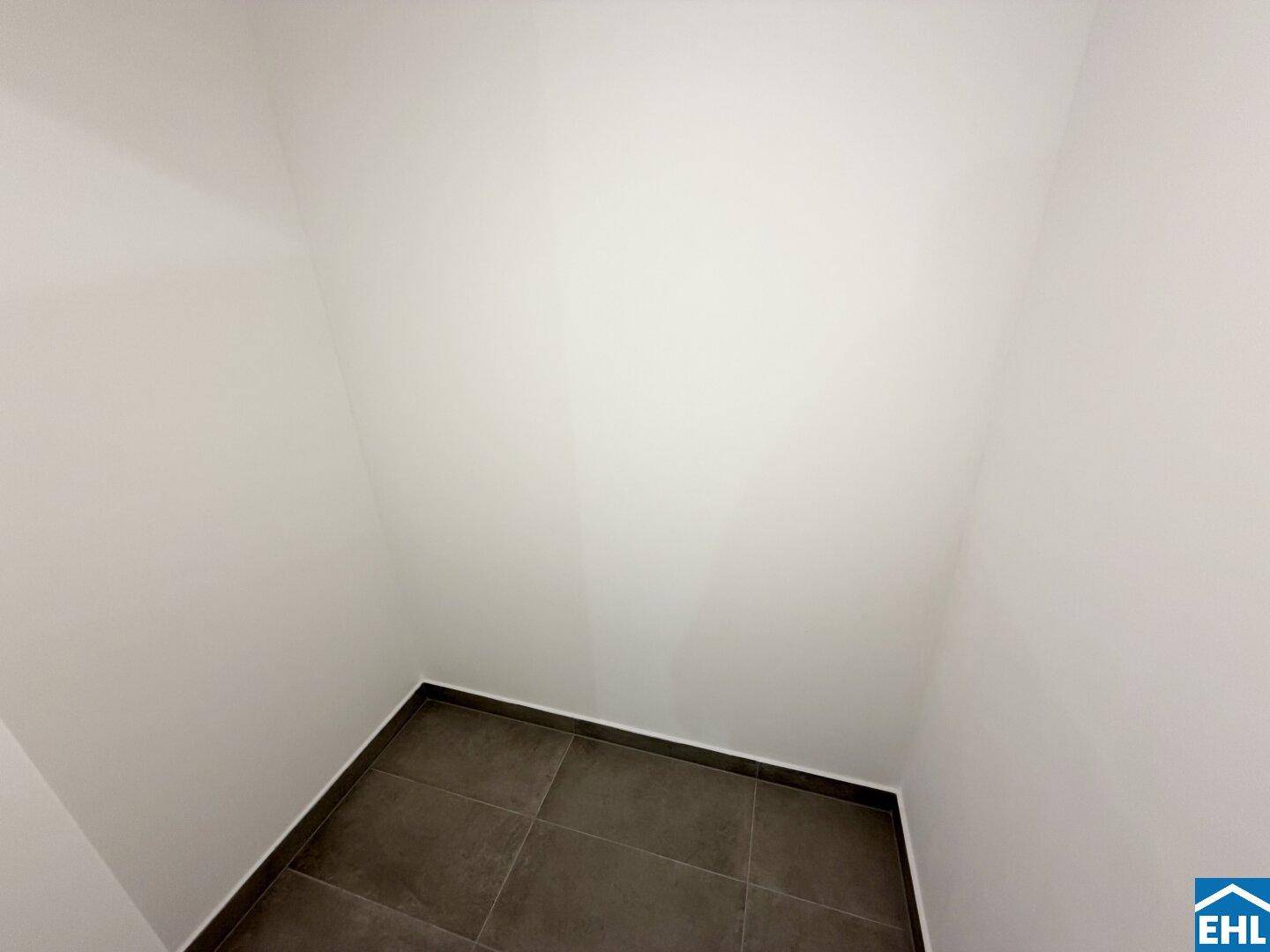 Kleiner Abstellraum mit Fliesenboden und weißen Wänden.