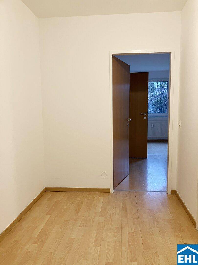 Heller Flur mit Parkettboden und Zugang zu einem weiteren Zimmer, in gutem Zustand.