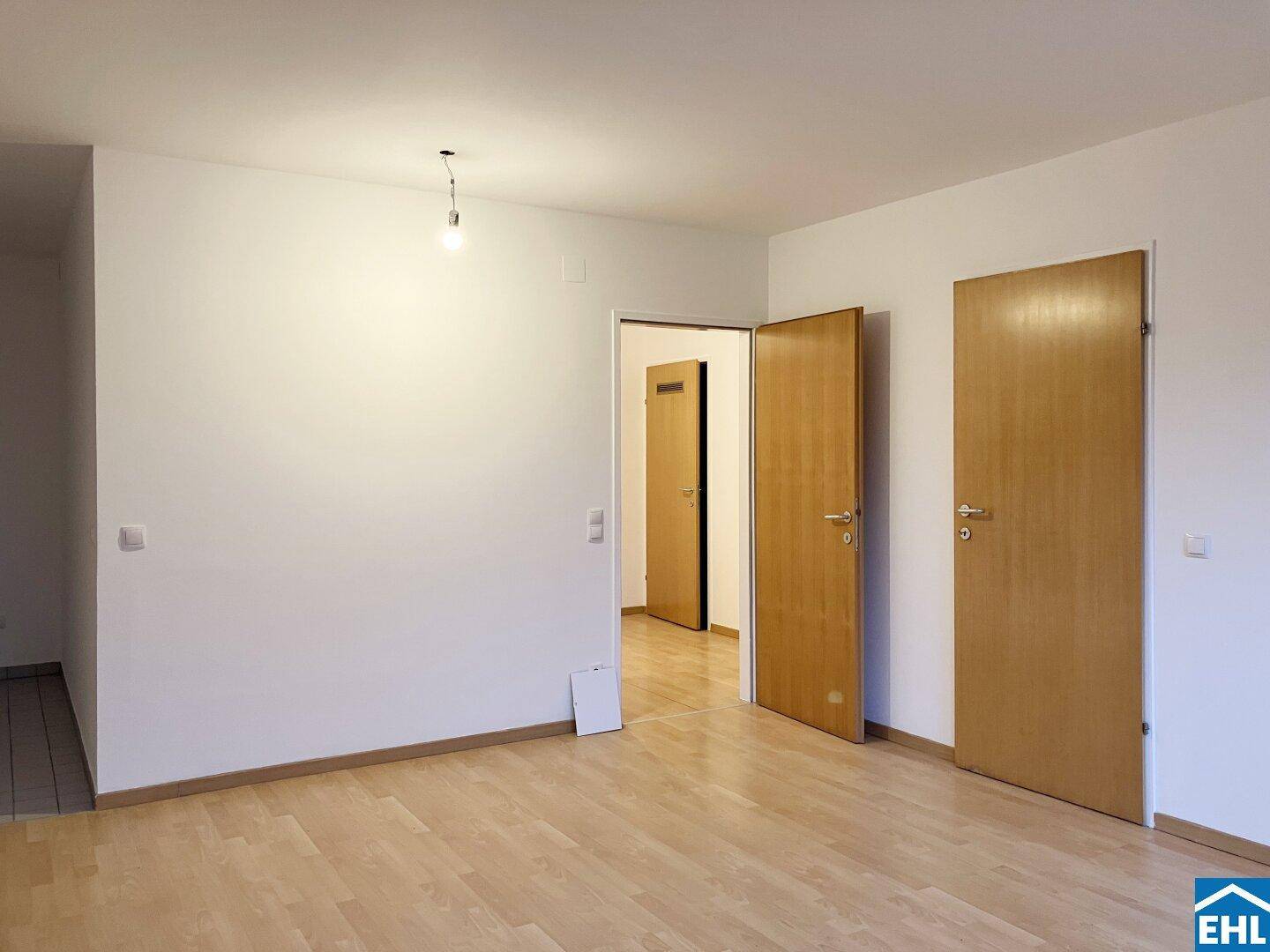 Geräumiger Wohnbereich mit Parkettboden und Zugang zu weiteren Zimmern durch Holztüren, in gutem Zustand.