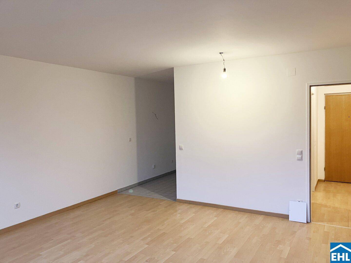 Heller Wohnbereich mit Parkettboden, der zu einem gefliesten Flur führt, in gepflegtem Zustand.