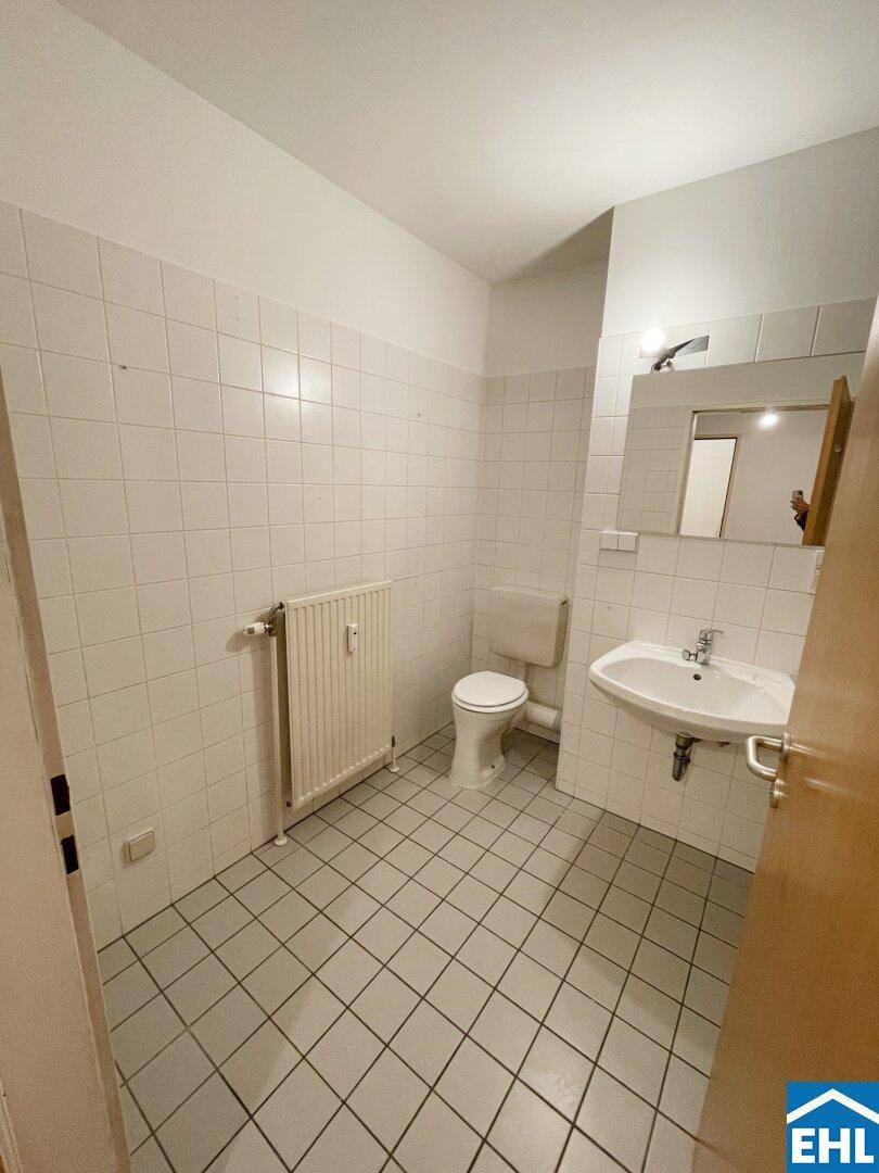 Gefliestes Badezimmer mit Toilette, Waschbecken und Heizkörper, in gutem Zustand.