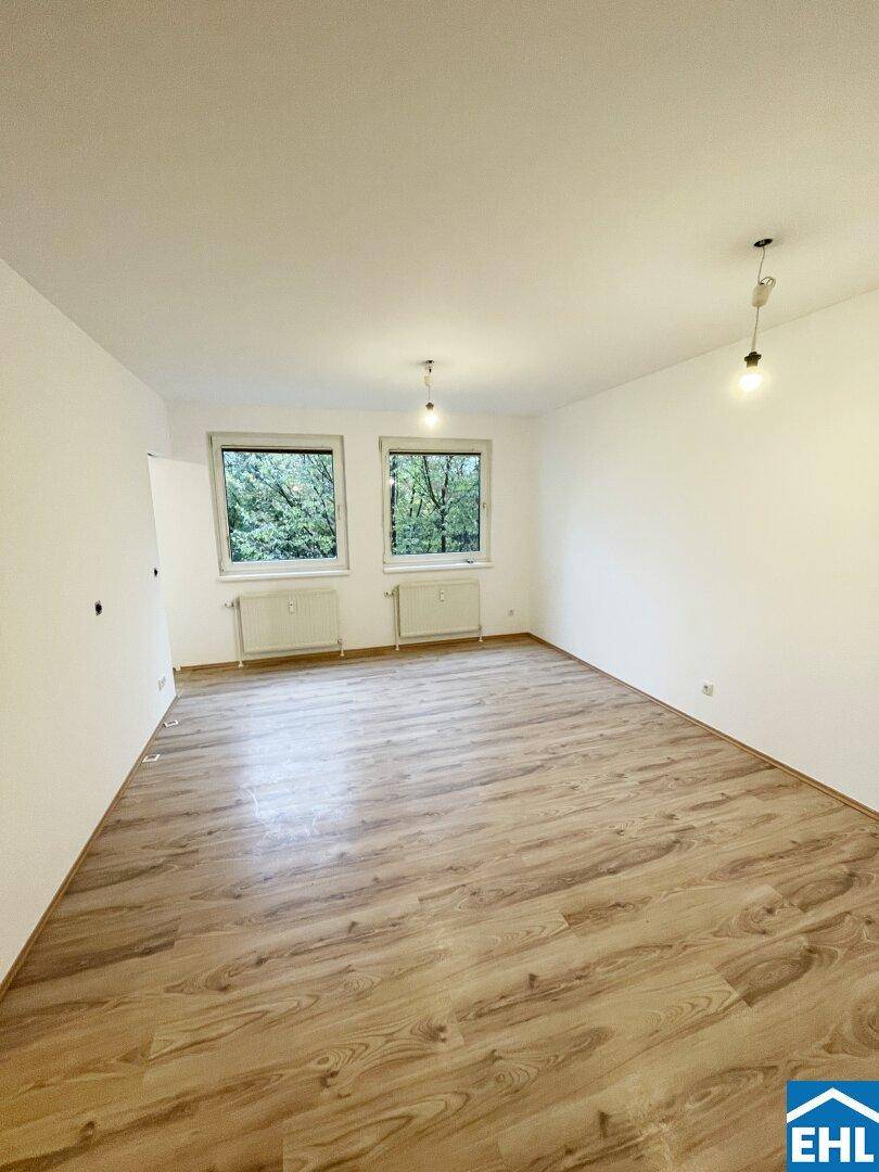 Lichtdurchfluteter Raum mit Laminatboden und Blick auf Bäume, ideal für ein Wohn- oder Schlafzimmer.