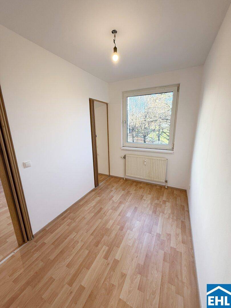 Gemütliches Zimmer mit Laminatboden, einem Fenster und Blick ins Grüne.