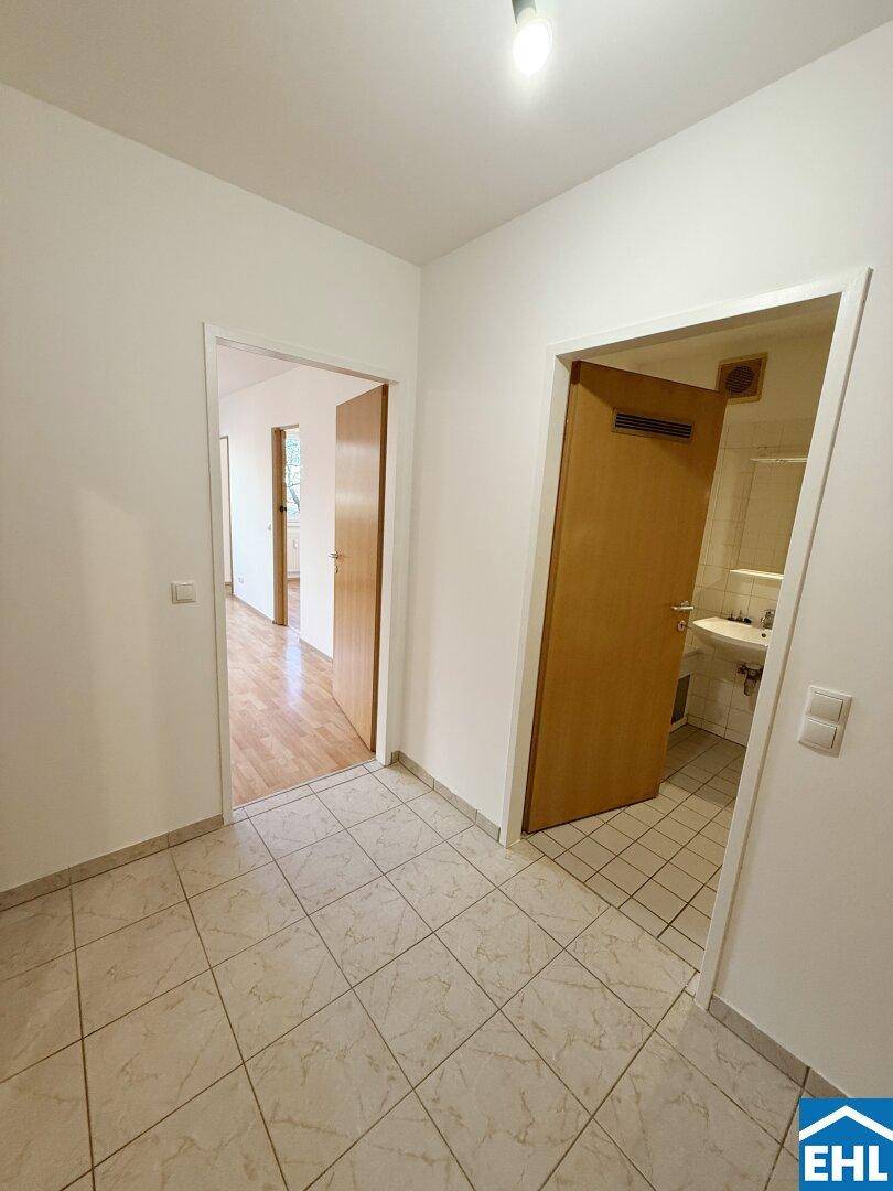 Heller Flur mit Fliesenboden und Zugang zu mehreren Zimmern und dem Badezimmer.