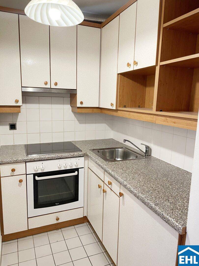 Funktionale Küche mit weißen Schränken, Granit-Arbeitsplatte und integriertem Herd.