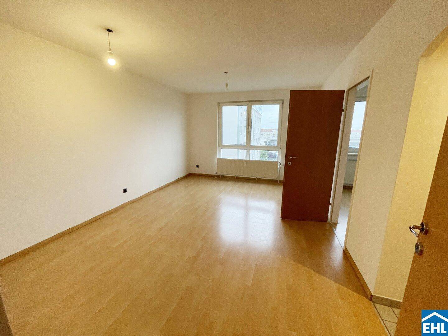 Geräumiges, helles Zimmer mit Parkettboden und Fenster, ideal für Wohn- oder Schlafbereich.