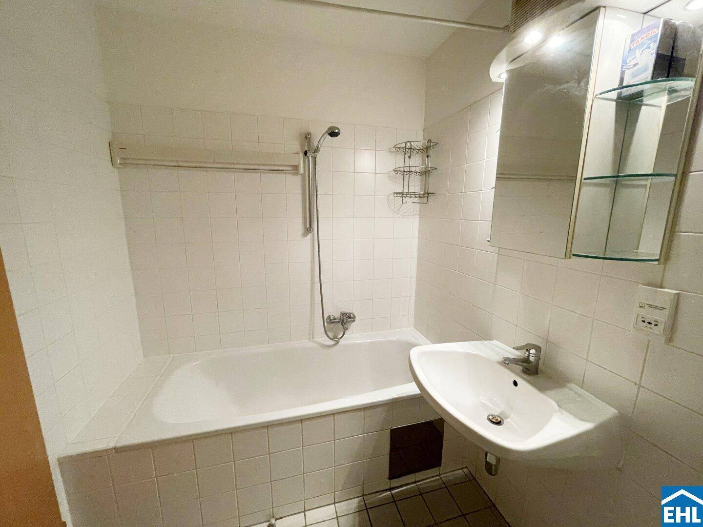 Badezimmer mit Badewanne, Waschbecken und weißen Fliesen, funktional und hell.