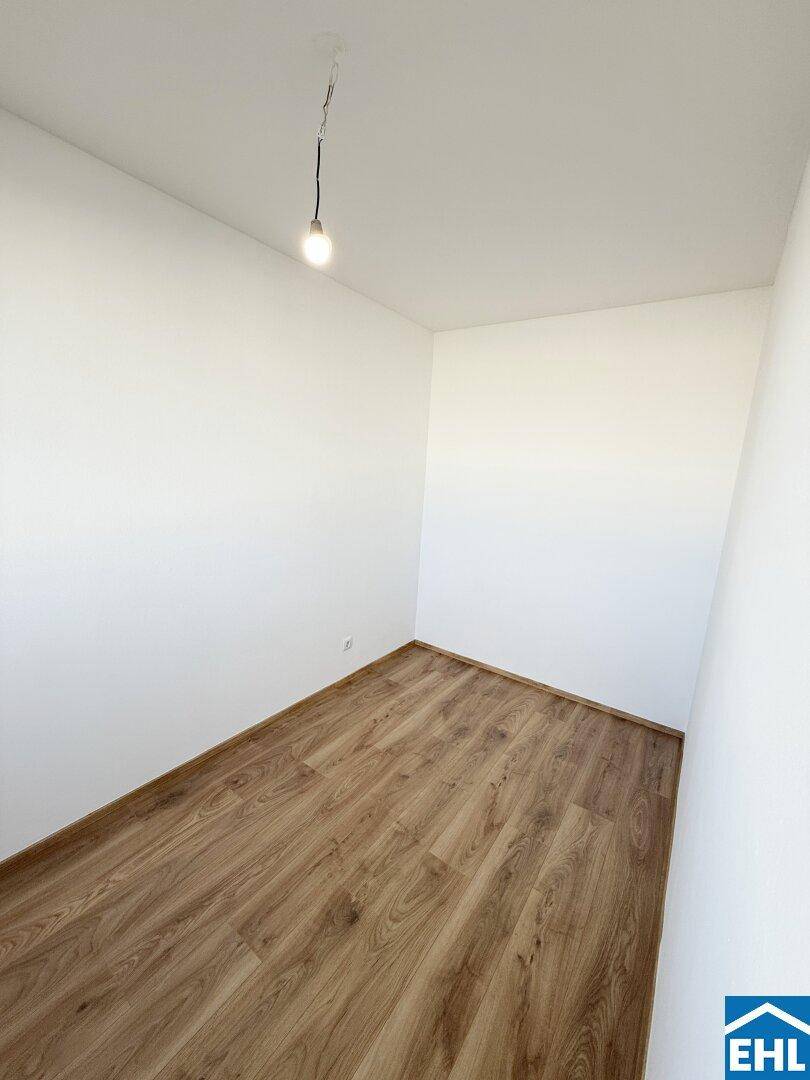 Leeres Zimmer mit Laminatboden und weißen Wänden, bietet eine neutrale Basis für Einrichtungsideen.