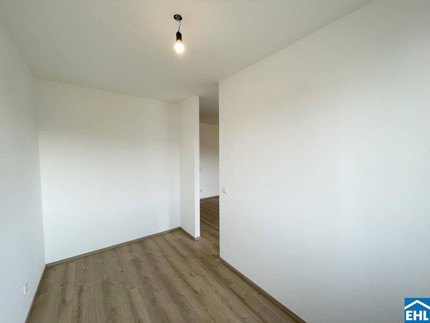 Leerer Raum mit Laminatboden und weiß gestrichenen Wänden, bietet flexible Nutzungsmöglichkeiten.