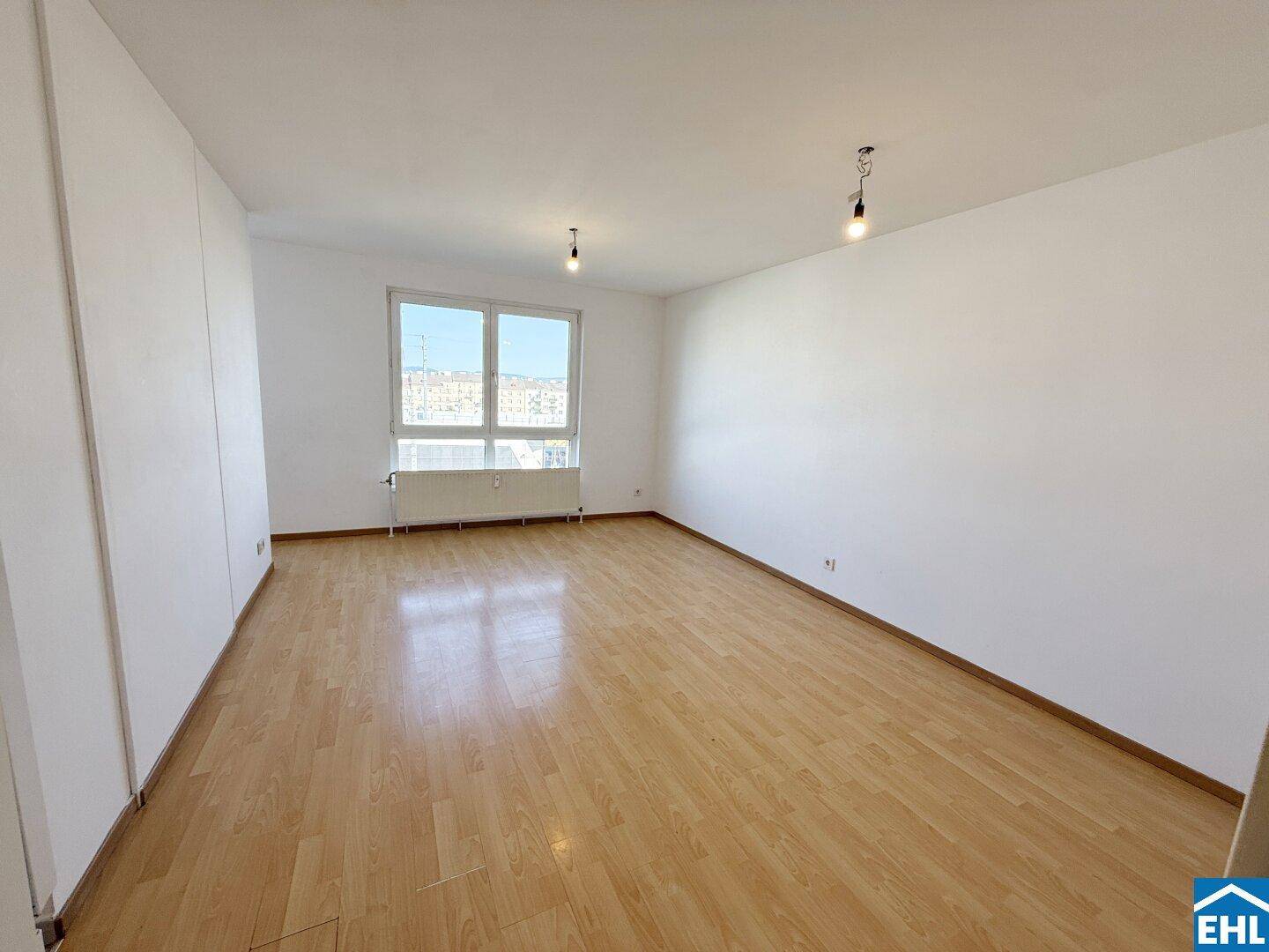 Geräumiges Schlafzimmer mit Laminatboden und großem Fenster für viel Tageslicht.