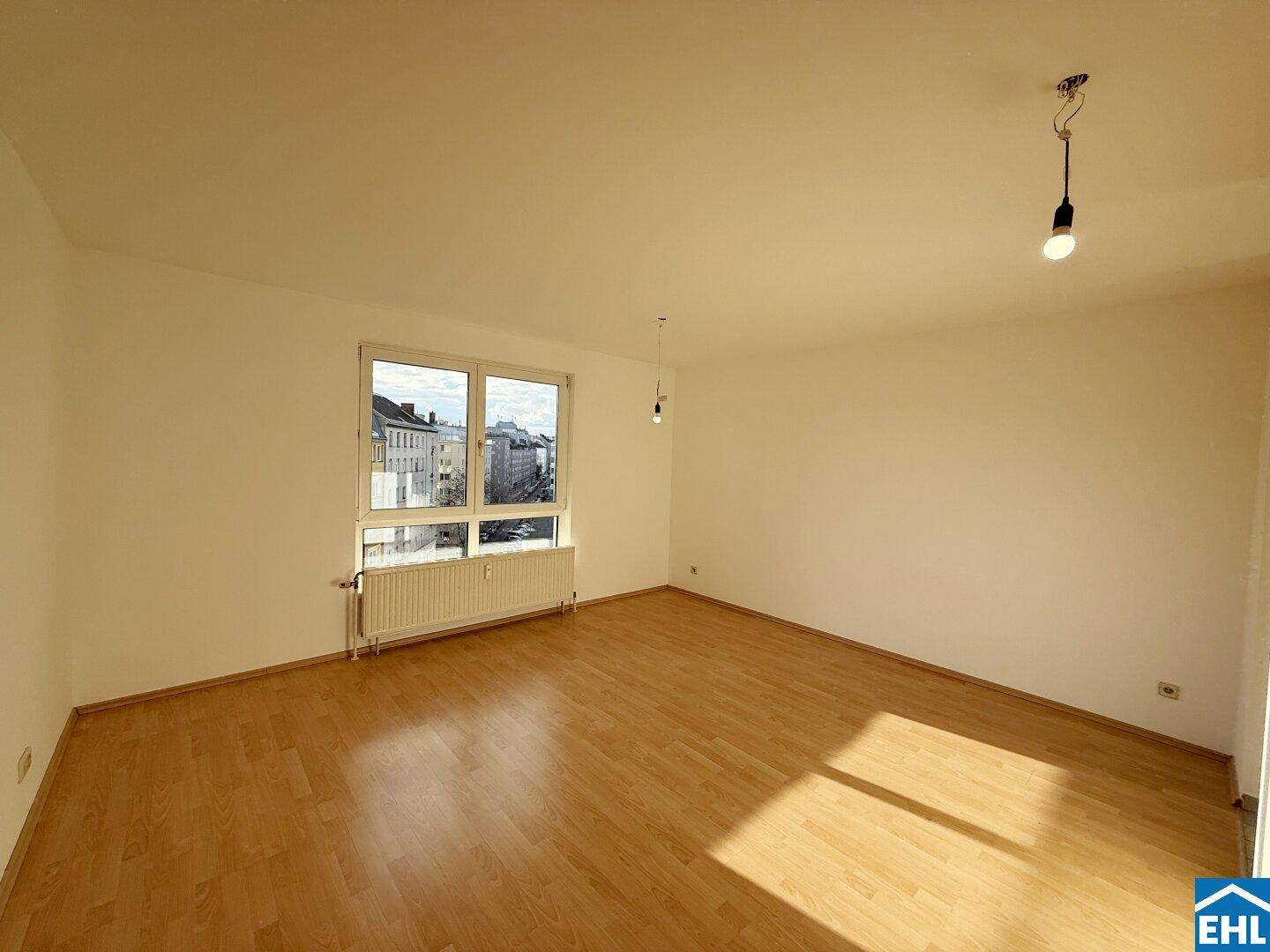 Lichtdurchfluteter Wohnbereich mit großem Fenster und Blick auf die Stadt.
