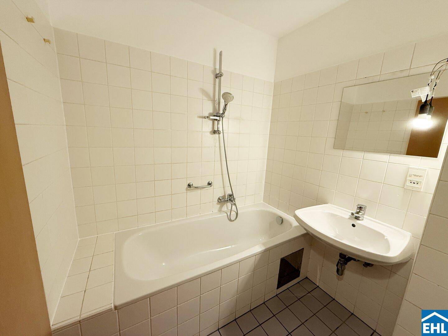 Badezimmer mit Badewanne, Waschbecken und weißen Fliesen, funktional und hell.