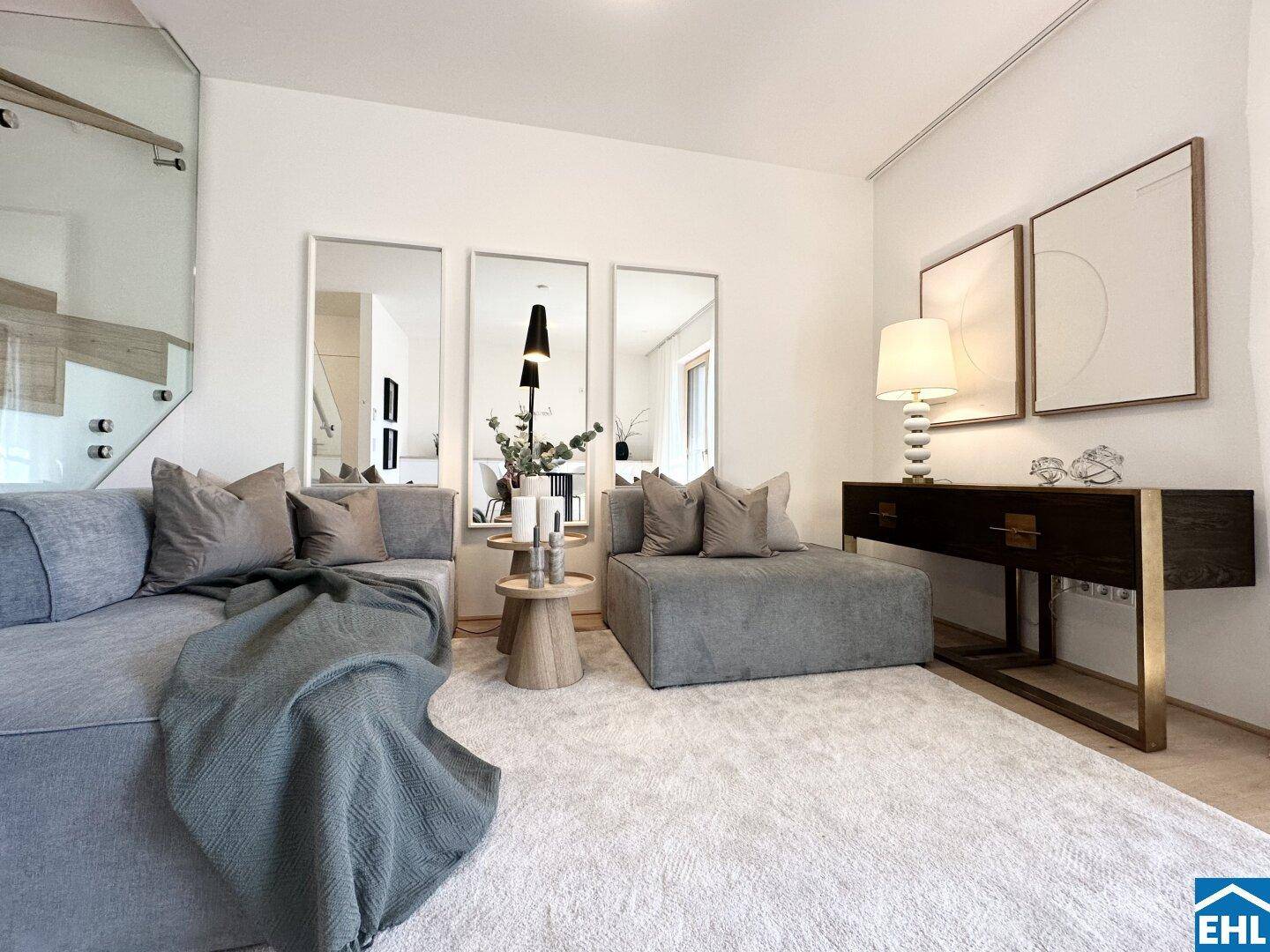 Geräumiges Wohnzimmer mit bequemen Sofas, großem Teppich und dekorativen Spiegeln an der Wand.
