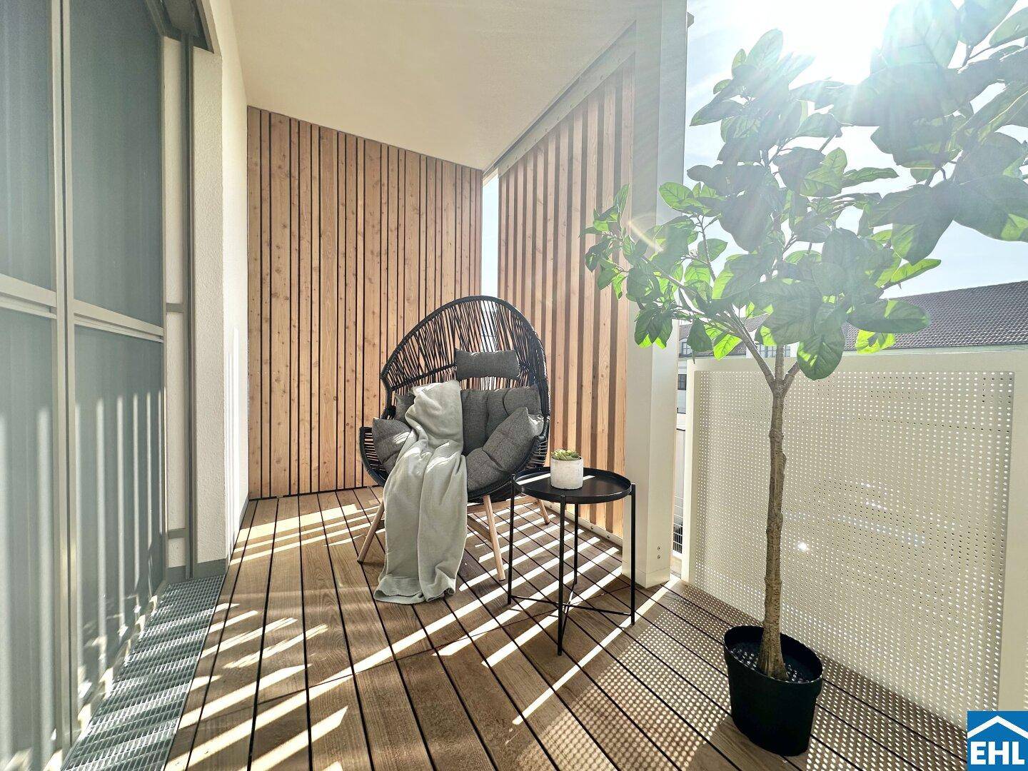 Sonniger Balkon mit Holzfußboden, bequemen Sitzmöbeln und dekorativer Bepflanzung.