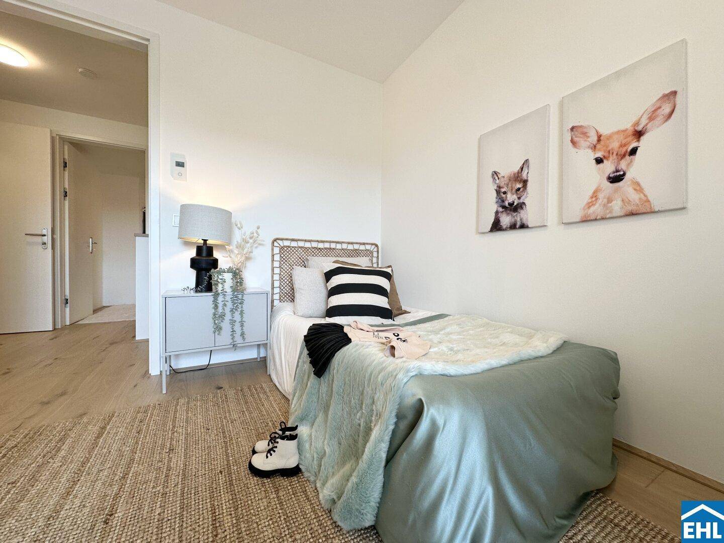 Kinderzimmer mit Einzelbett, Teppich und niedlichen Tierbildern an der Wand.